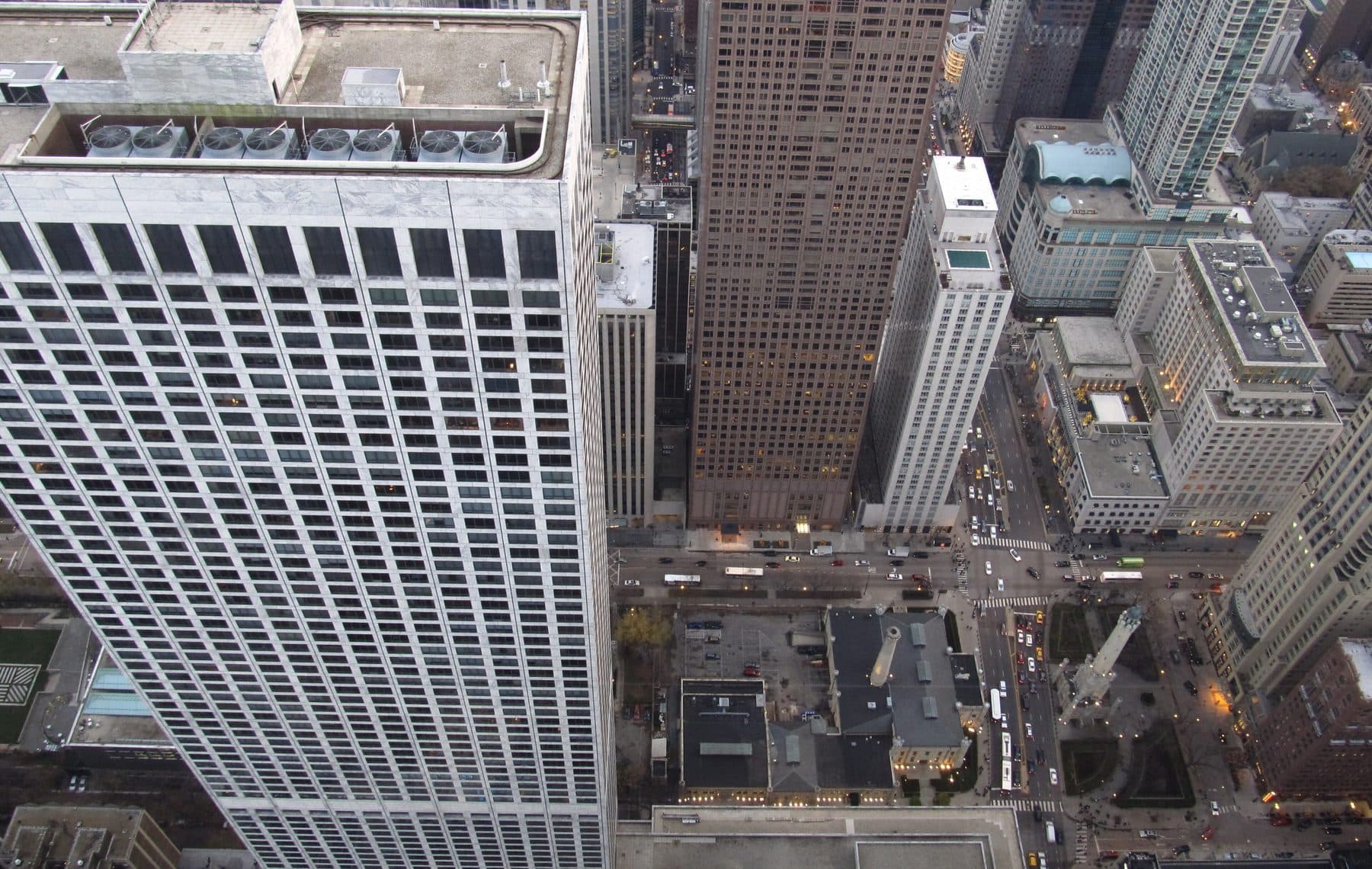 Looking straight down at the street grid from the John Hancock observatory, with a white tower in the foreground.